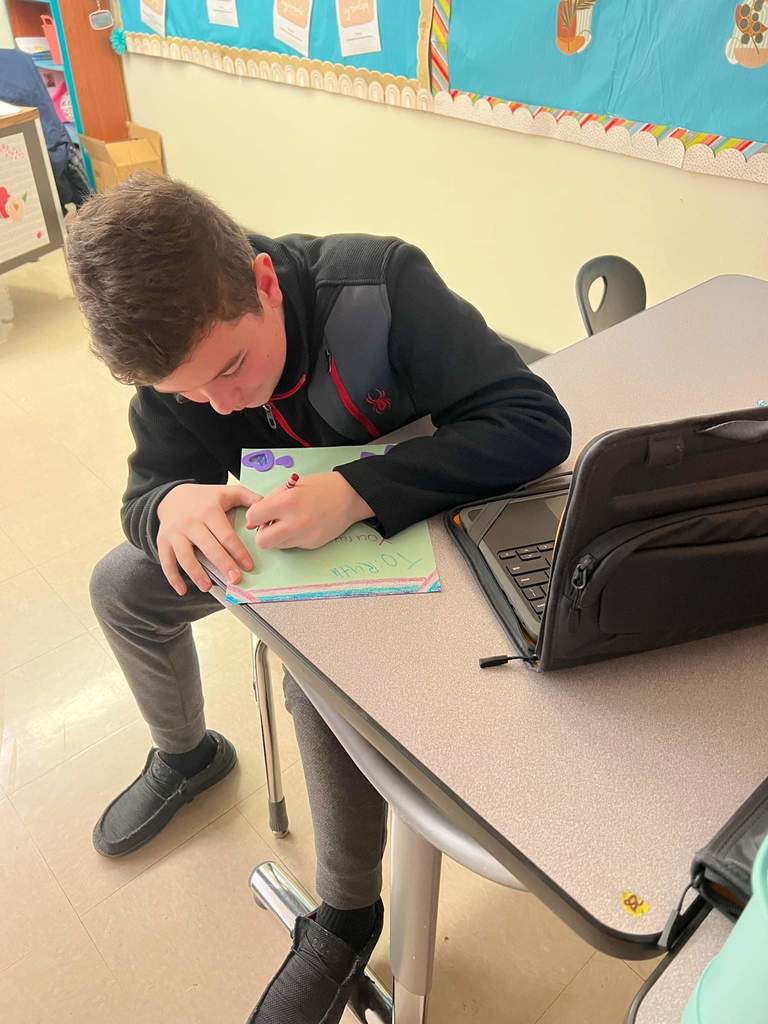 Student writing out Valentine's Day Project on Green paper