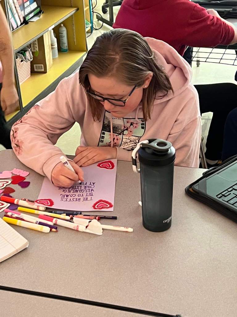 Student working on Valentine's day card with markers and purple paper