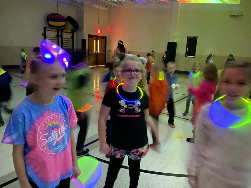students looking toward camera during glow party (partial blurred from motion)